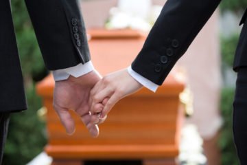 People holding hands at the funeral of a wrongful death victim in Virginia.