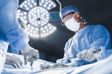 Group of surgeons at operation in operating room at hospital.